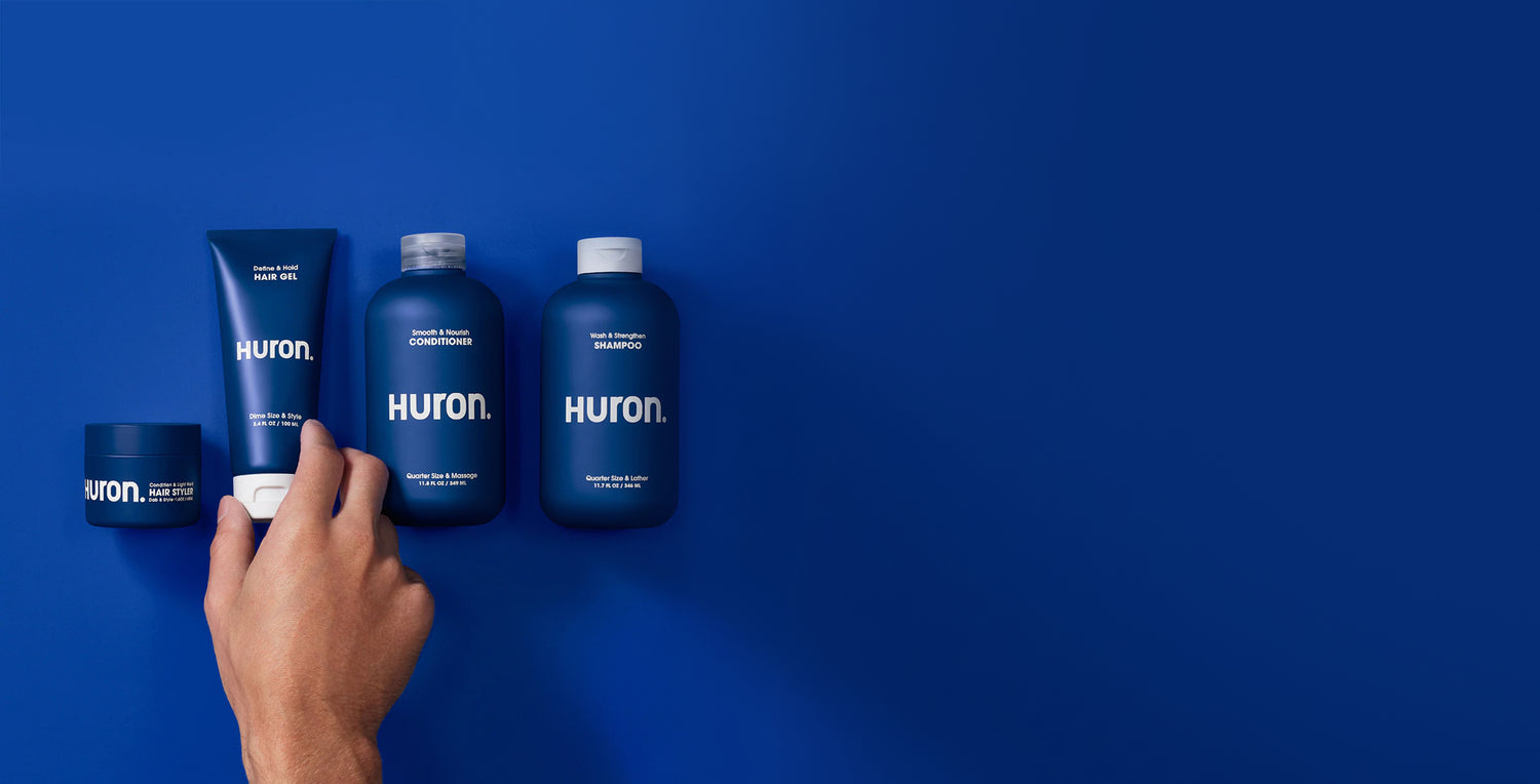 Shampoo, conditioner, hair gel, and hair styler bottles are lined up against a deep blue background.