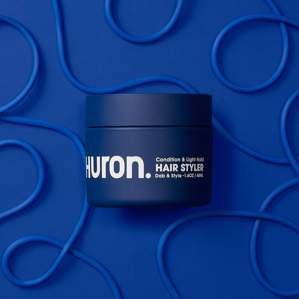 A pot of hair styler lies against a dark blue background.