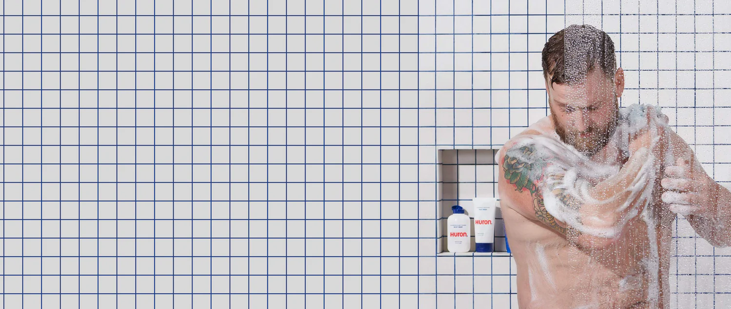 A man lathers up using a loofah in the shower. 