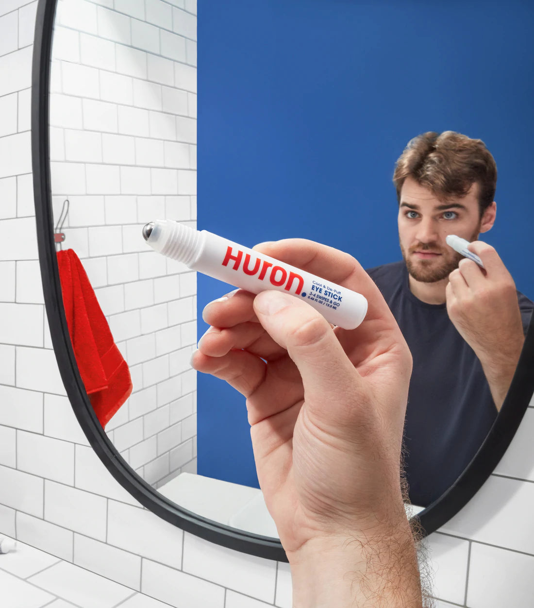 A man applies an eye care product using a bathroom mirror. 