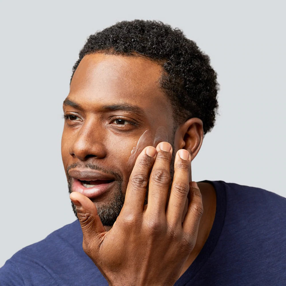 A man applies moisturizer to his face. 